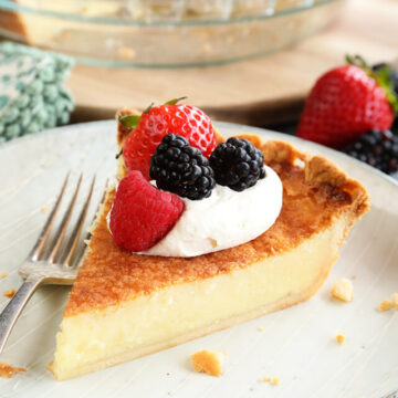 Slice of Buttermilk Pie with whipped topping and fruit on top