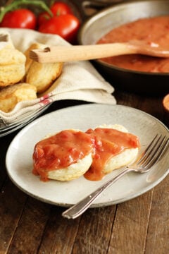 Biscuit covered with Southern Tomato Gravy with homemade biscuits in backbround
