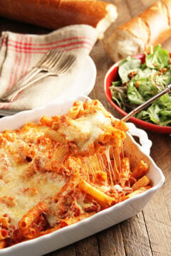 Cheesy Baked Ziti in casserole dish being served with spoon