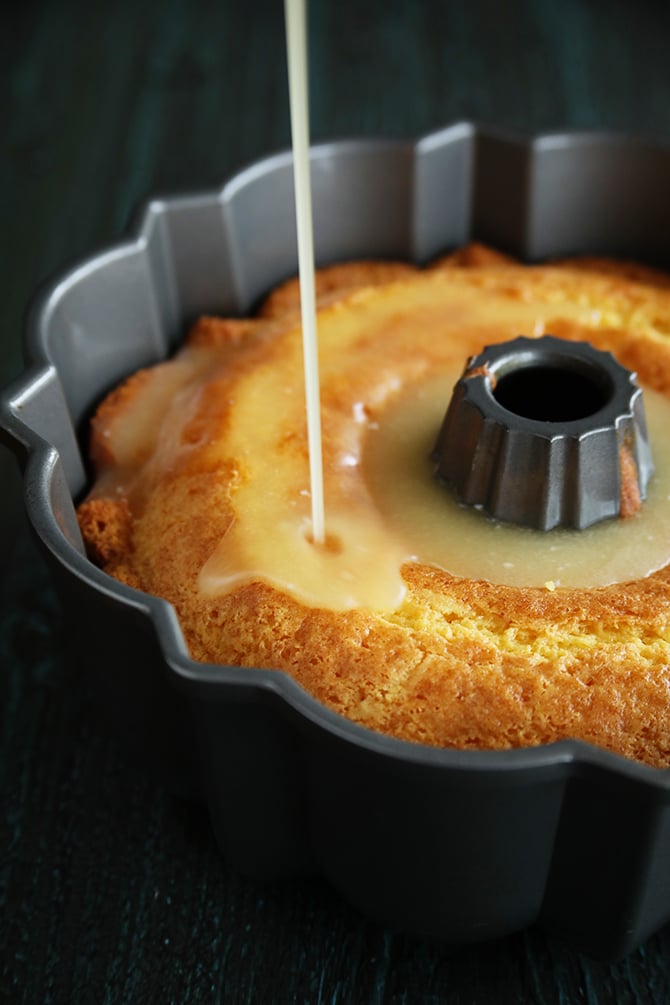 Pineapple juice Cake in pan while pouring glaze on top