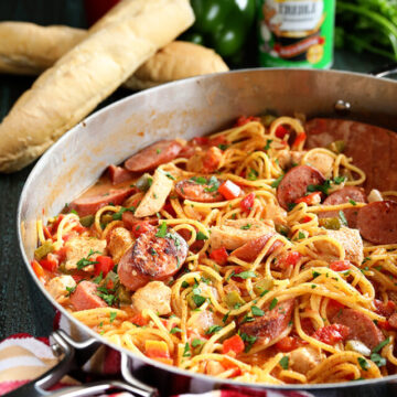 Creamy One Pot Jambalaya Pasta in pan with seasoning and bread in back ground