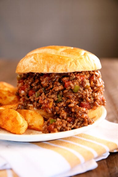 Creole Sloppy Joes on a white plate with potato wedges
