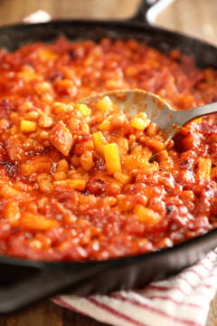 Spoonful of Bacon Pineapple Baked Beans in a cast iron skillet