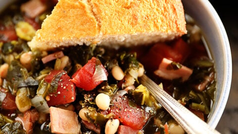 Bowl of Collard Green Soup with Ham and Beans with cornbread