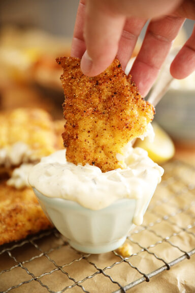 Piece of Fish being dipped into Dill Pickle Tartar Sauce