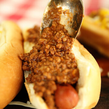 Spooning Hot Dog Chili Sauce onto hot dogs