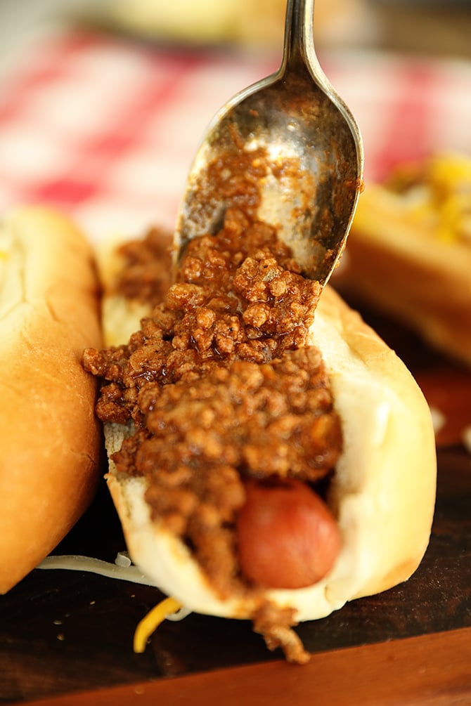 Spooning Hot Dog Chili Sauce onto hot dogs