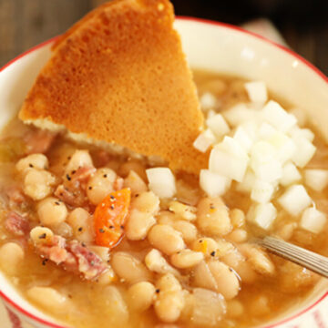 Slow Cooker Ham and Beans in bowl with cornbread and onions