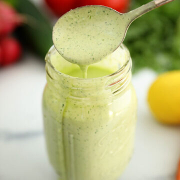 Pouring Green Goddess Salad Dressing into a jar.