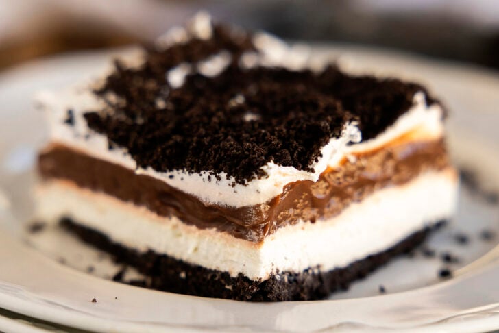 One piece of Oreo Delight on a stack of white plates.