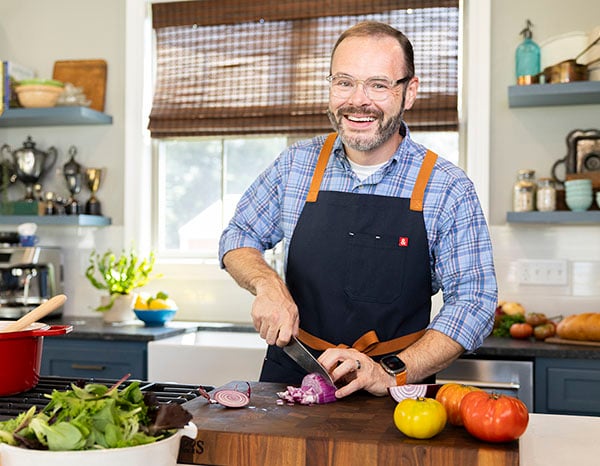 Stacey Little cutting vegetables on cutting board in kitchen