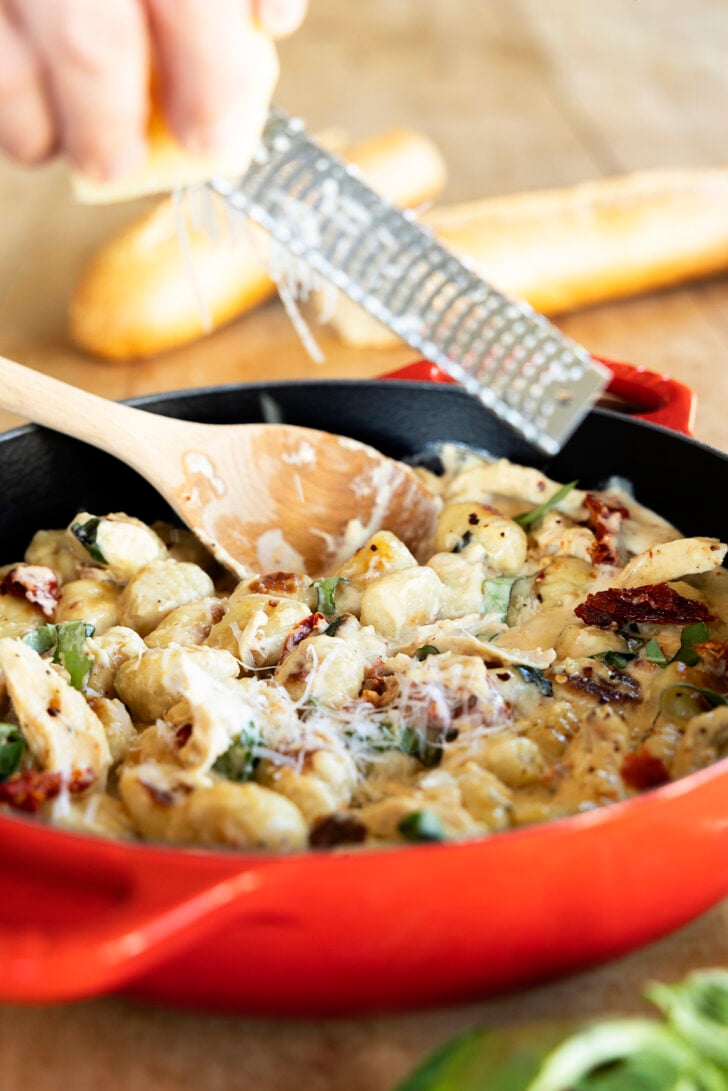 Grating cheese over dish.